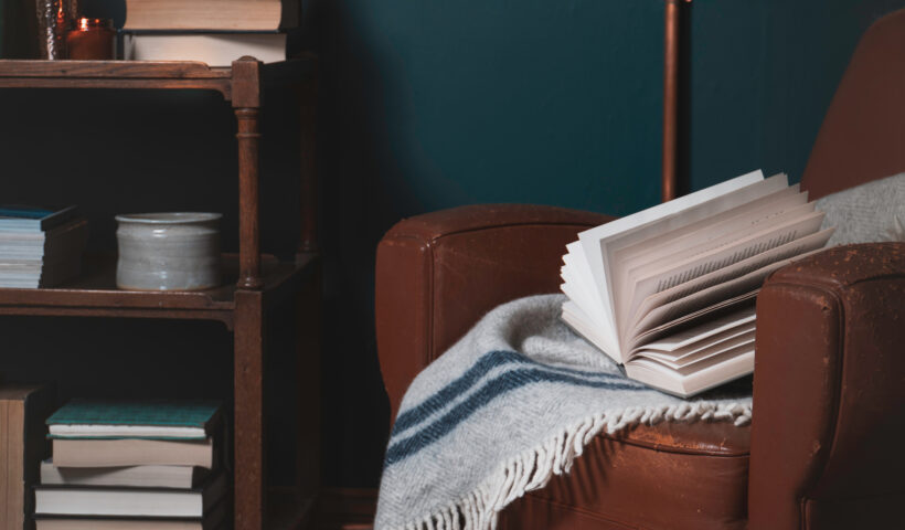 worn brown leather chair, blue wall, bookshelf, books, gray and blue throw blanket decorating tips for small spaces,