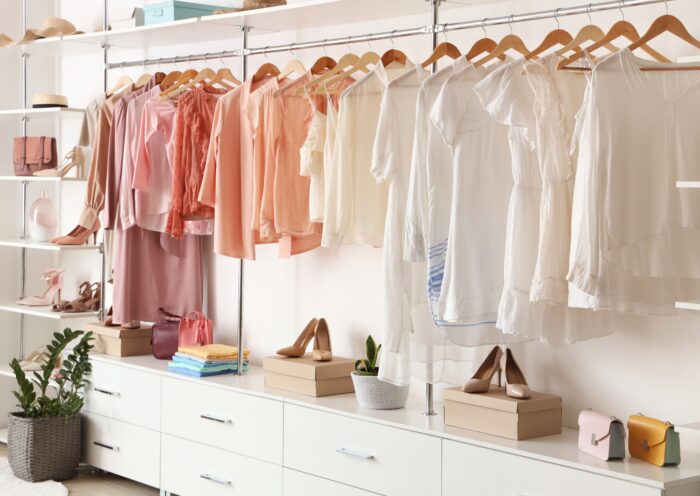 decluttering tips closet white peach pink clothing wooden hangers white shelves and drawers decluttering tips organized open closet