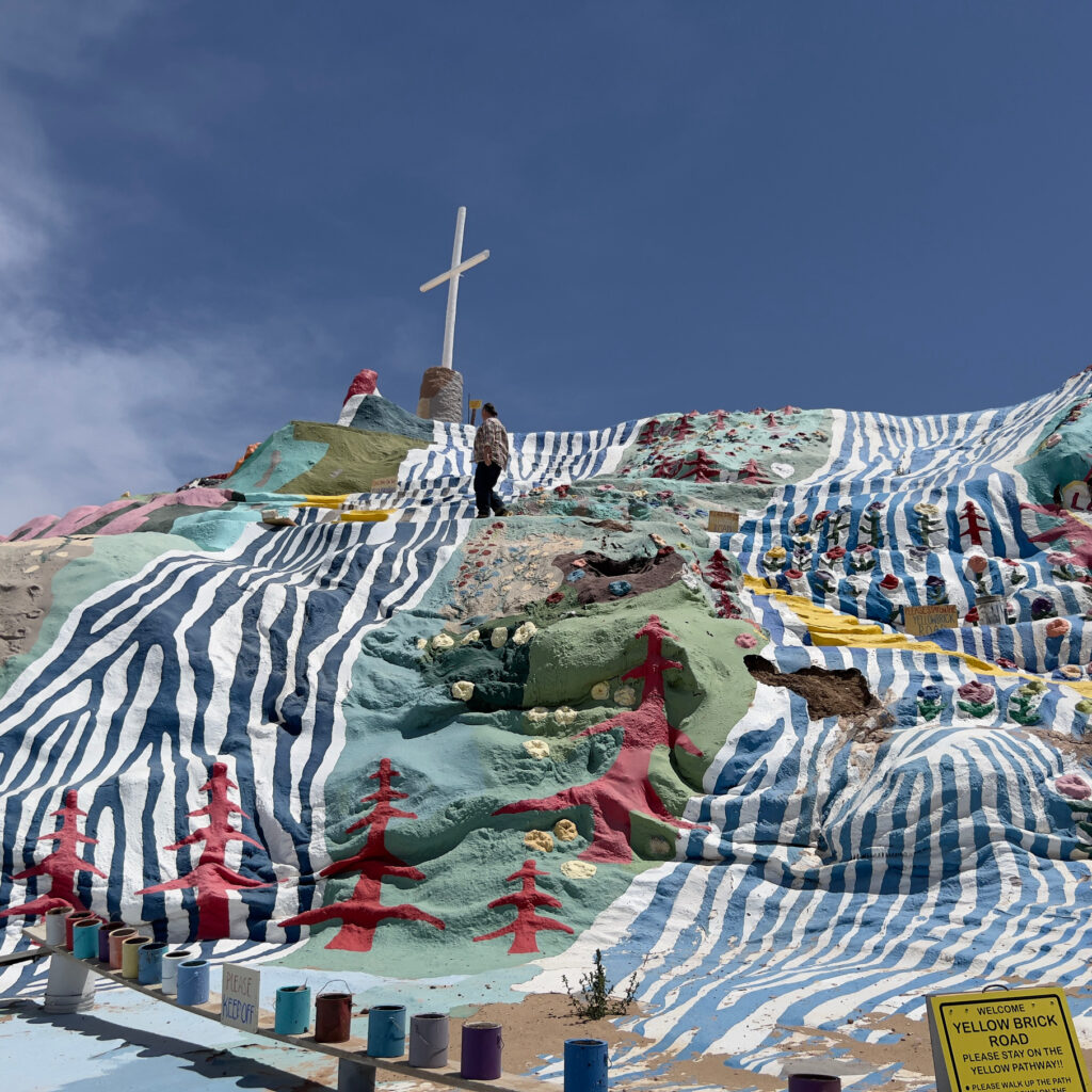 Salvation Mountain against a deep blue sky Andy following the yellow painted road Travel Art by Leonard C Knight Those Someday Goals