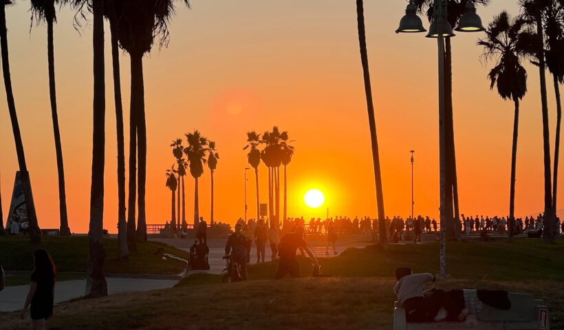 Sunset and an orange sky against palm trees with people milling in the background of Venice Beach, California Those Someday Goals Things that make me smile