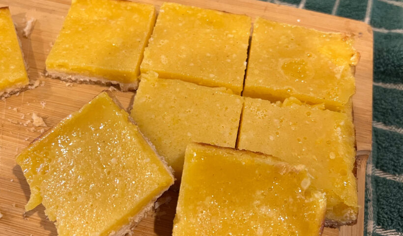passion fruit bars on a wooden cutting board next to a knife and a green and white checked cloth Those Someday Goals