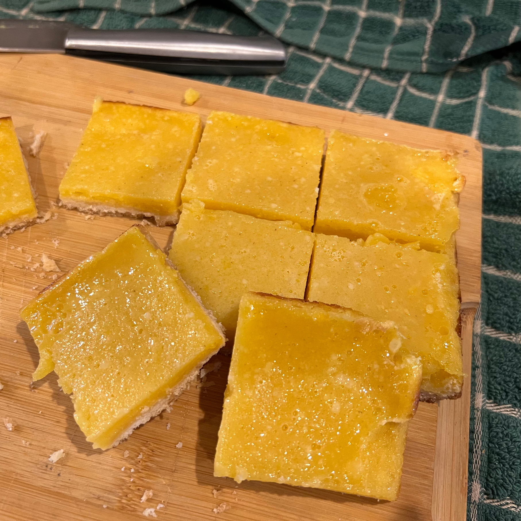 passion fruit bars on a wooden cutting board next to a knife and a green and white checked cloth Those Someday Goals
